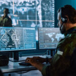 Military Surveillance Officer Working on a City Tracking Operation in a Central Office Hub for Cyber Control and Monitoring for Managing National Security, Technology and Army Communications.