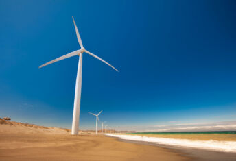 Ninety One eyes launch of global EM infrastructure debt strategy targeting up to $1bn Wind turbines along ocean shore sustainable and renewable energy landscape view